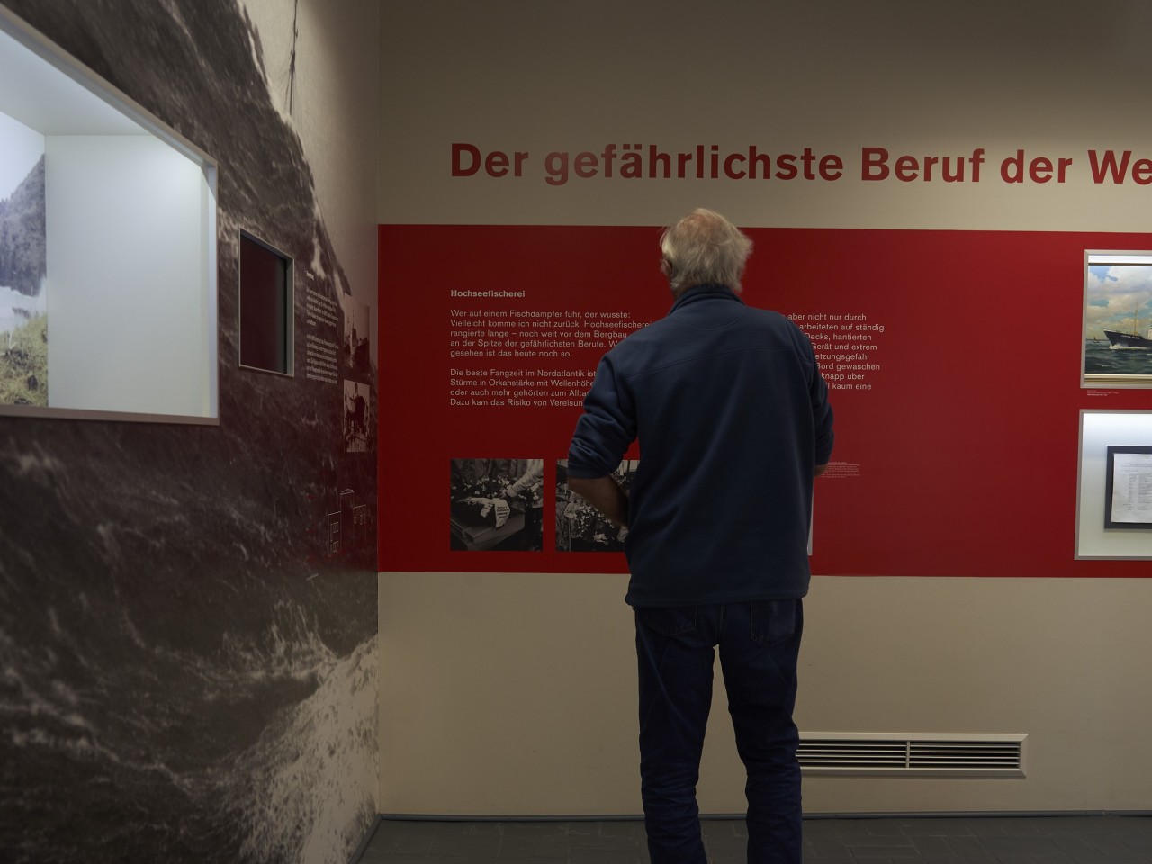 Ein Mann liest den Text "Der gefährlichste Beruf der Welt" im Raum "In Seenot"